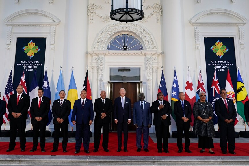 Biden stands in the middle of 12 of the Pacific Island leaders, and their respective flags.