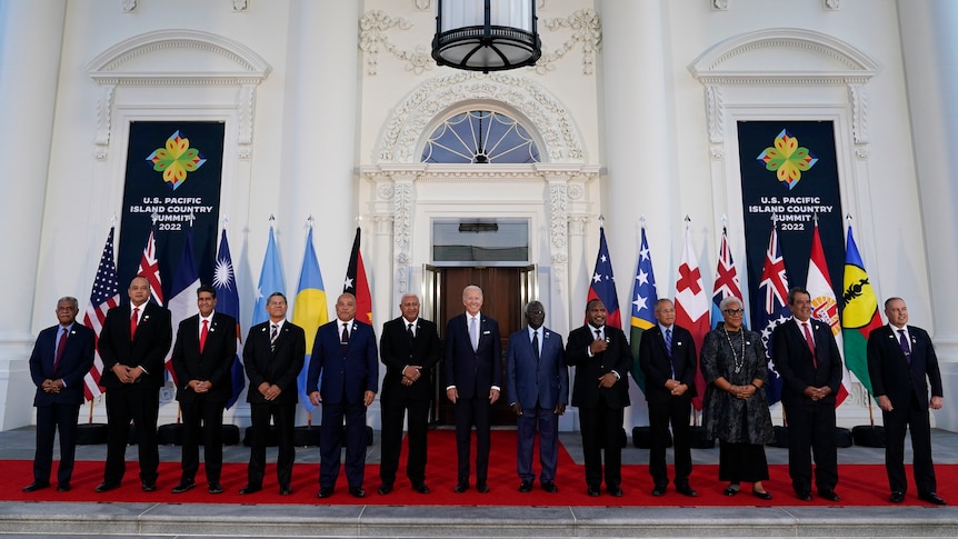 Biden stands in the middle of 12 of the Pacific Island leaders, and their respective flags.