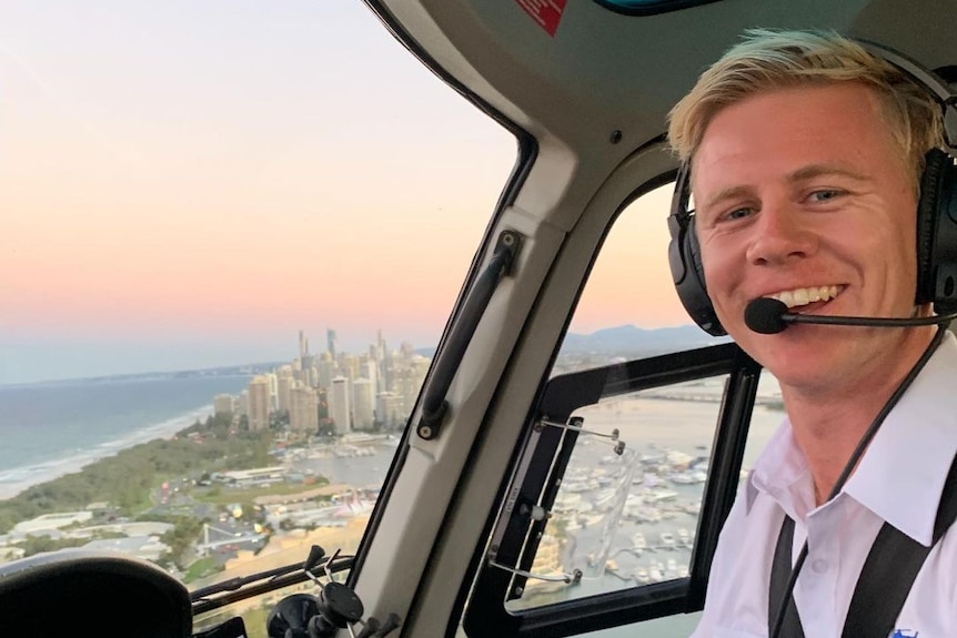 Un jeune homme aux cheveux blonds en uniforme souriant dans le cockpit d'un avion.