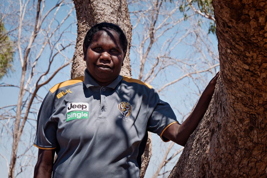 A photo of Indigenous woman Lisa Smiler leaning on a tree near Kalkarindji.