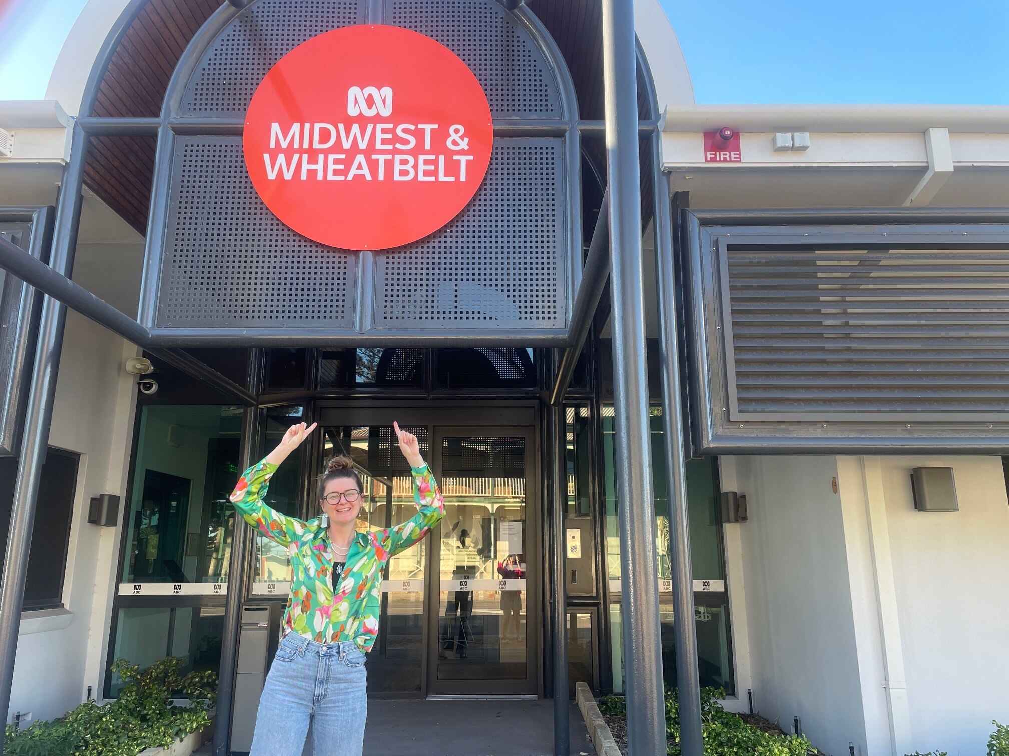 Dan Hamilton in bright shirt points at an ABC Midwest Wheatbelt sign