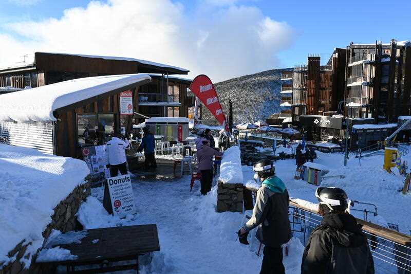 Personas con equipos de esquí se abren camino a través de la nieve hasta una cafetería en un pueblo alpino.
