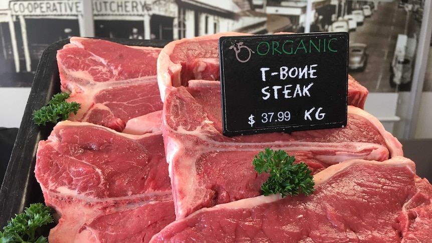 A tray of red meat at a butcher, with a black price sign on the top right.