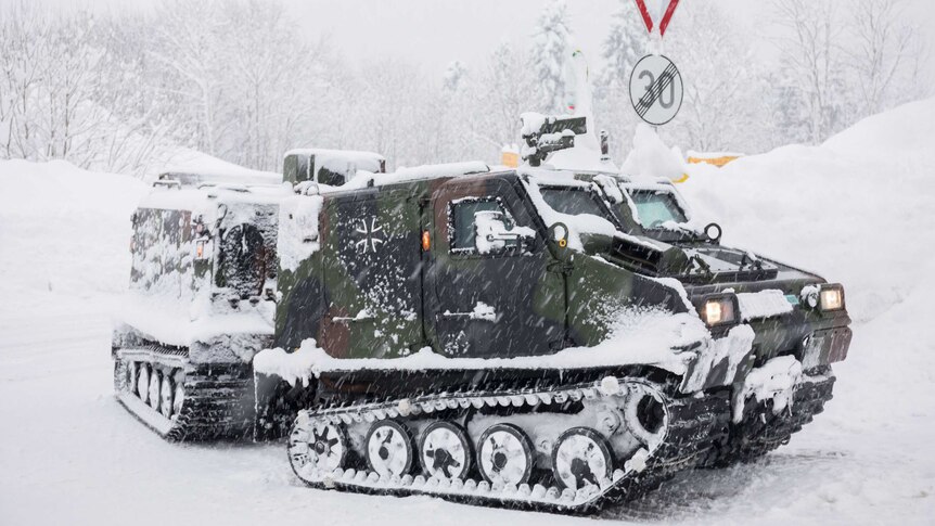 An army tank driving in the snow
