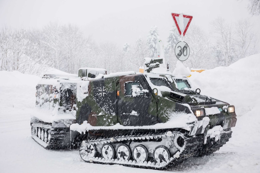 An army tank driving in the snow