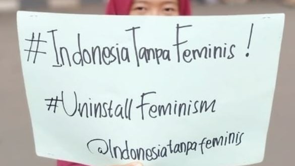A woman holds up a sign saying Indonesia Tanpa Feminis.