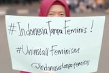 A woman holds up a sign saying Indonesia Tanpa Feminis.