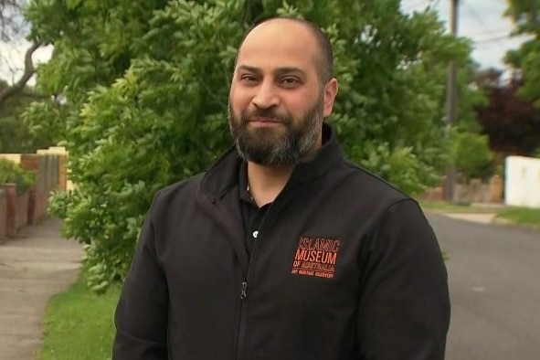 A man with a beard standing outside.