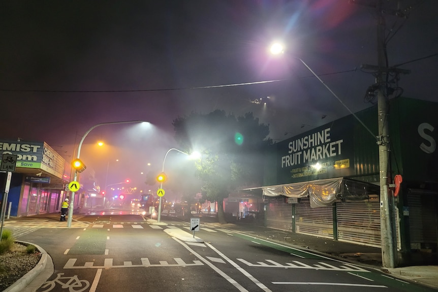 A smoky road at night with fire trucks in the distance.