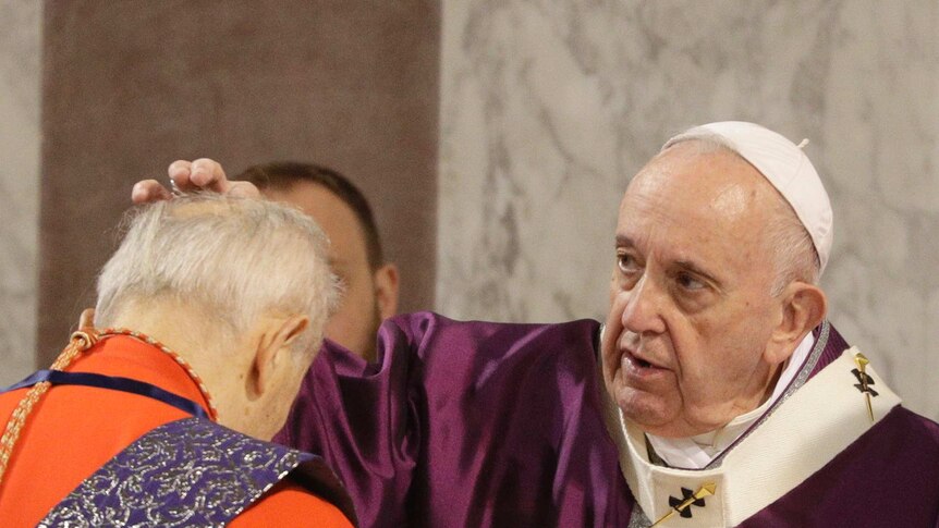 The pope dressed in purple puts ashes on a man's forehead
