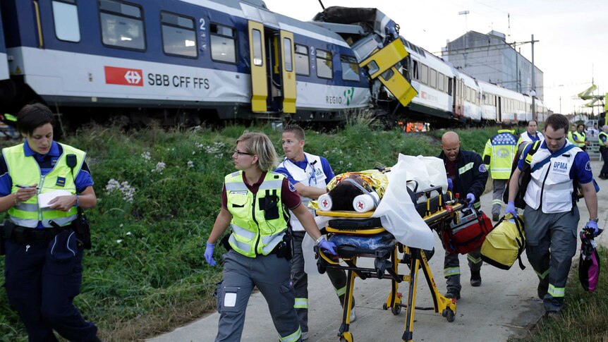 A passenger is taken away on a stretcher after being injured in a train collision in Switzerland.