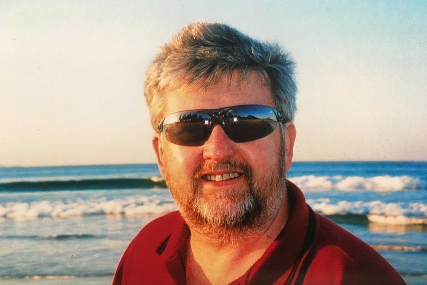 A man in sunglasses at the beach.
