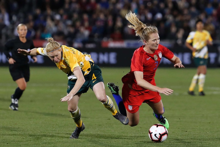 Clare Polkinghorne stumbles to the ground with her arms up as Sam Mewis (in red) also falls to the ground