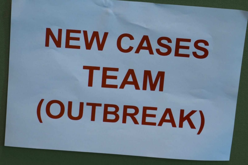 A sign pinned to an office partition reading: New cases team (Outbreak)