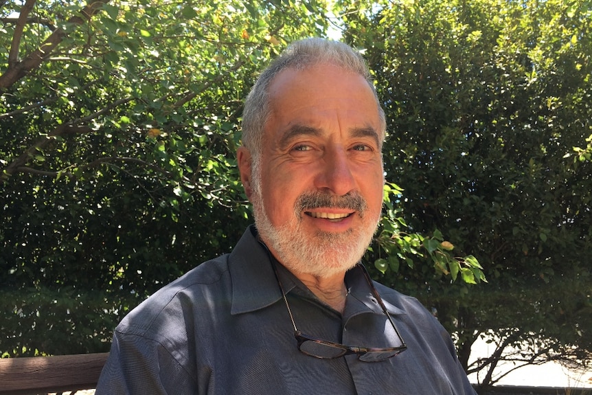 A man sitting on a bench in front of trees