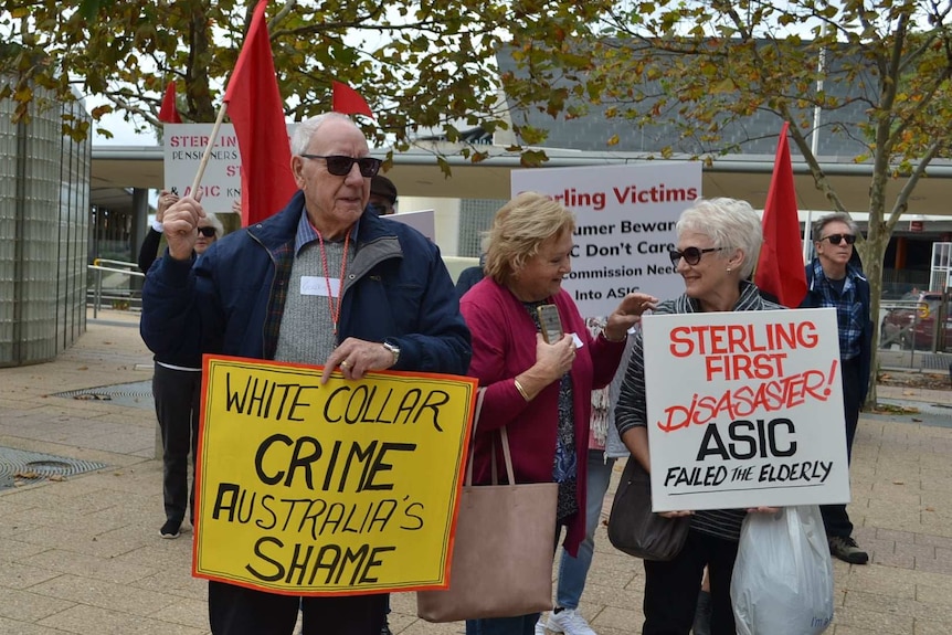Several men and women hold placards saying things like: "White Collar Crime Australia's Shame".