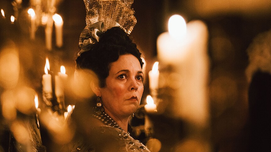 Colour close-up of Olivia Colman amongst candles in 2018 film The Favourite.