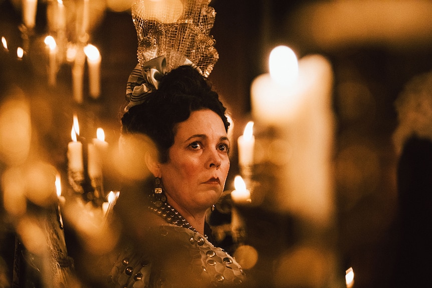 Colour close-up of Olivia Colman amongst candles in 2018 film The Favourite.
