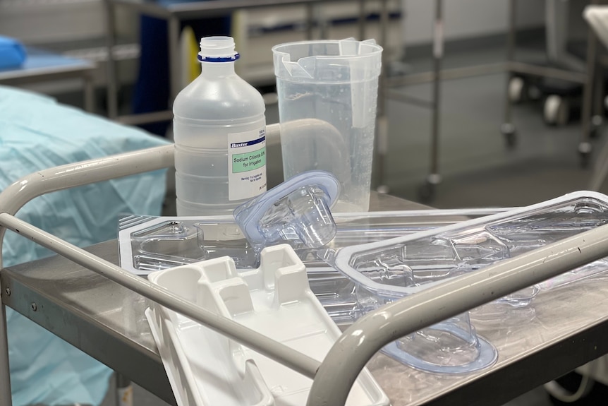 A tray of used plastic containers on a metal trolley in a hospital.