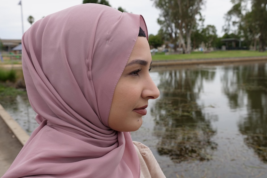 A close up photo of a woman staring out across a lake 