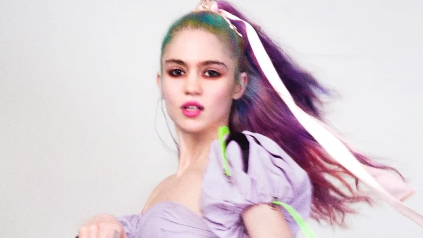 Grimes, dressed in purple top, ribbon in her purple and green hai