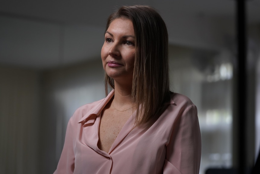 Woman looks into the distance while sitting in a dark office.