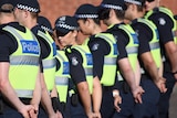 Police officers in yellow vests stand in a row.