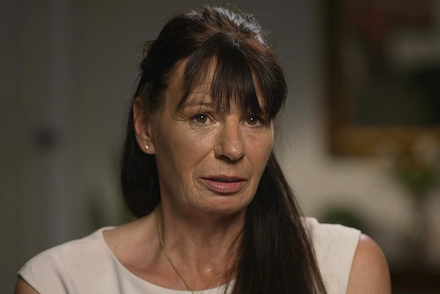 A woman with long dark hair wearing a white top.