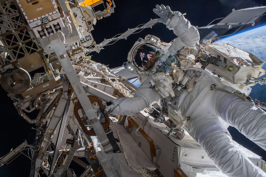 An astronaut wearing a space suit is pictured on the ISS during a spacewalk to install gear. 