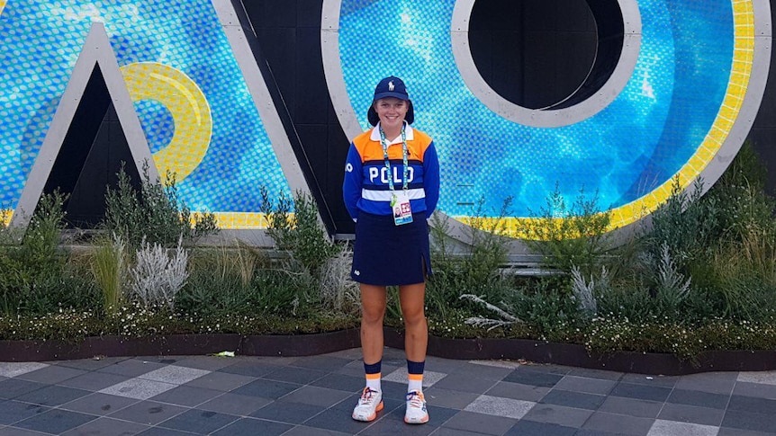 girl in ball kid uniform stands in front of AO sign