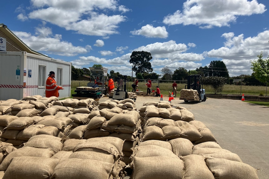 A row of sandbags men in orange uniforms are preparing 