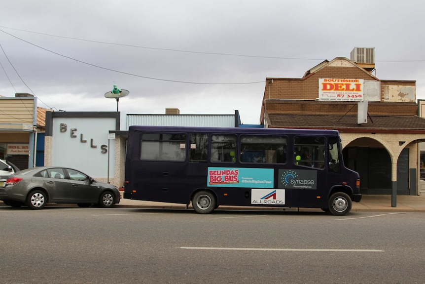 A purple bus parked on the street in front of Bell's Milk bar in Broken Hill