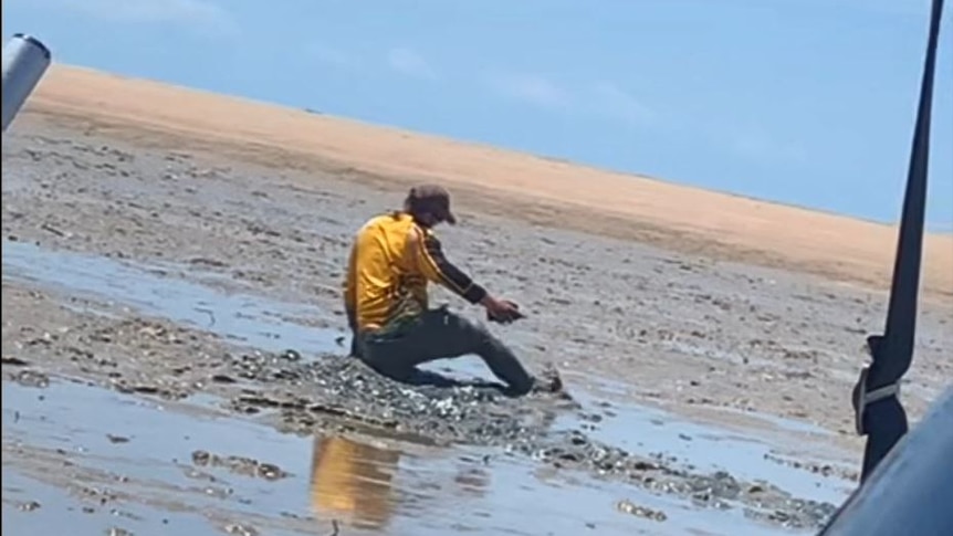 Man attempts to walk through mud at Shoal Bay