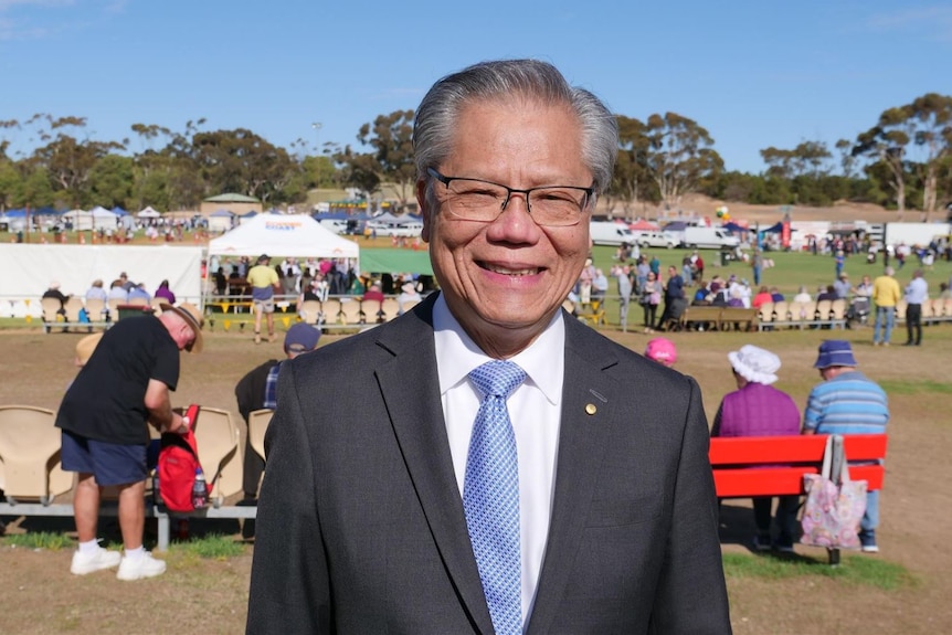 A man smiles with a busy festival in the background.