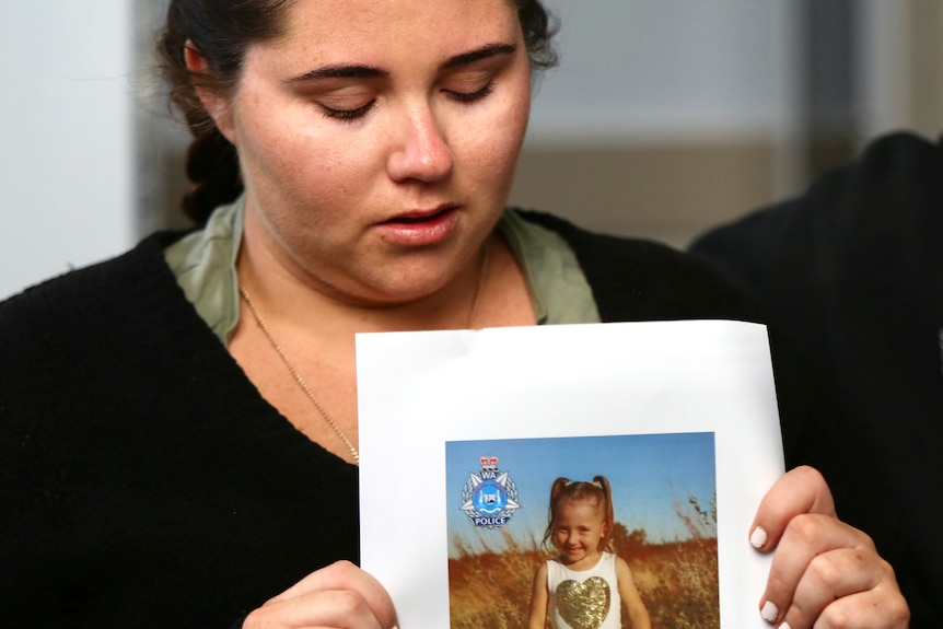 A crying woman holds a photo of a child.