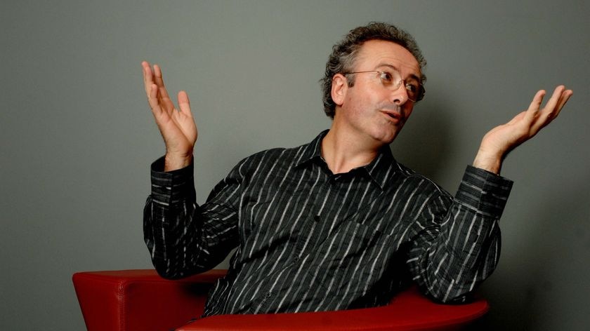 Andrew Denton posing in a red chair