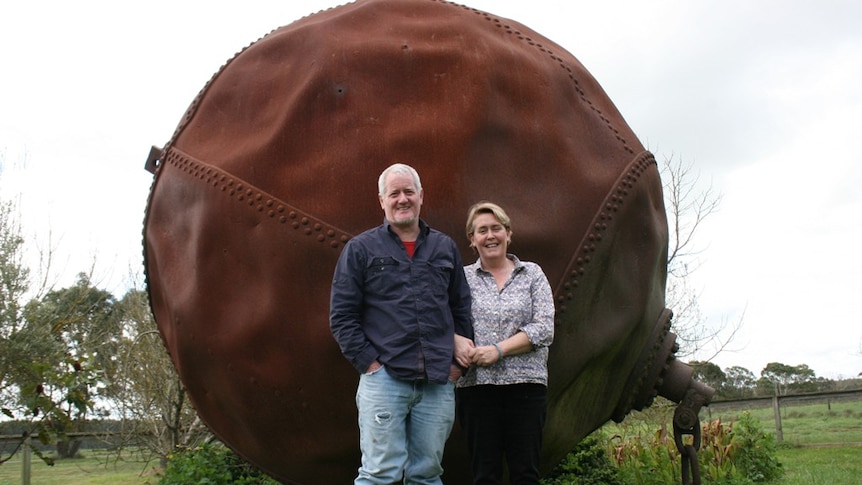 Man and woman standing next to a huge steel ball