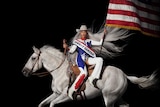 Beyonce on a white horse, carrying an American flag and wearing red, blue and white, with a white cowboy hat on