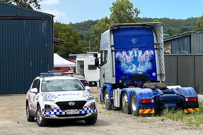 A police car parked in a commercial yard next to a truck
