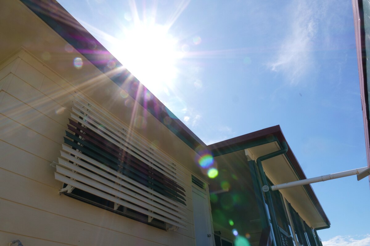 The sun is shining on the roof of a house.