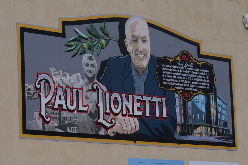 A large painting on a wall featuring a man in a suit and a title saying Paul Lionetti.