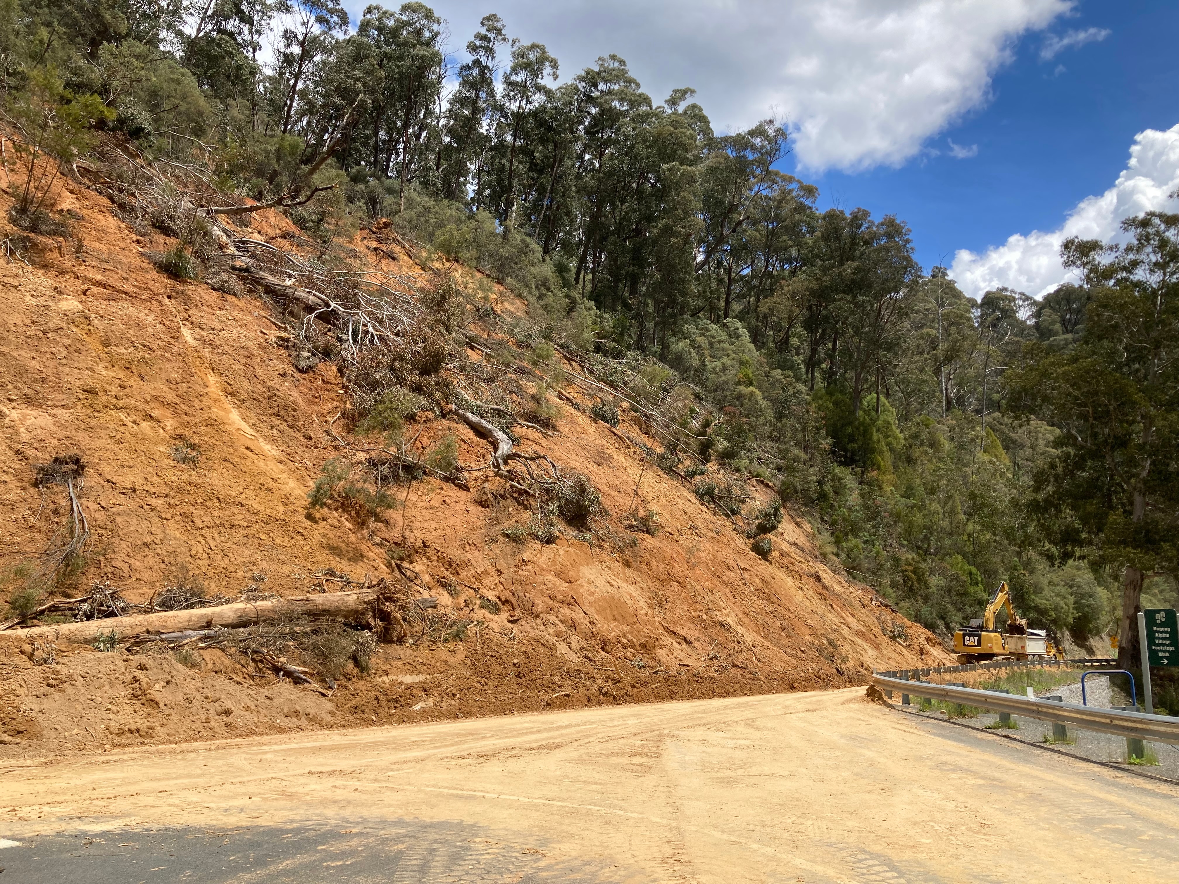 Landslide running down to a road with a bulldozer.