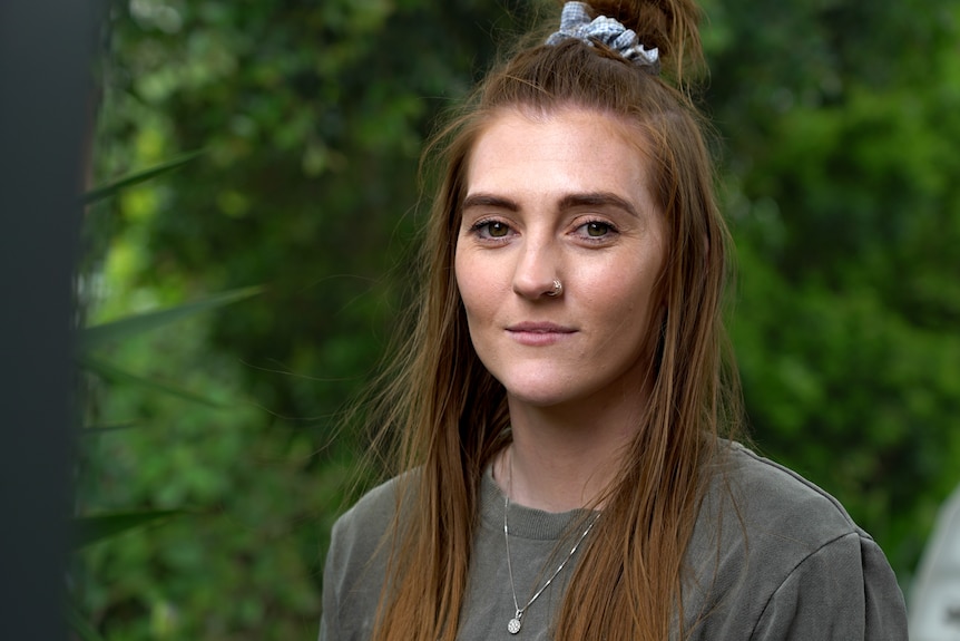 A portrait of a woman with hair half up portrait against greenery