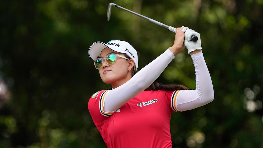 Australian golfer Minjee Lee looks through dark glasses as she completes her swing on a tee-shot.
