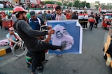 Protesters hit a poster showing Iraqi Prime Minister Adel Abdel-Mahdi with shoes.