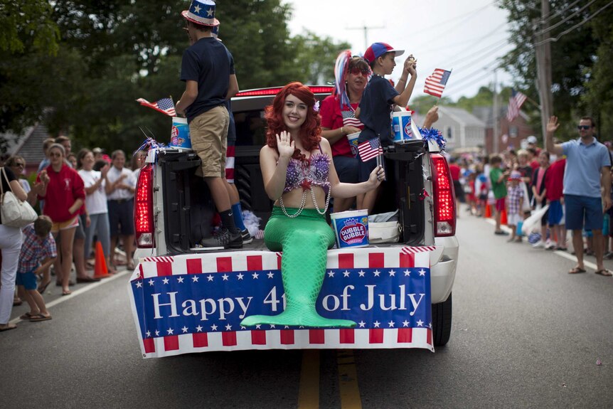 A girl dressed as a mermaid rides in an Independence Day parade in Massachusetts