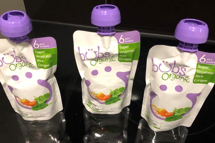 Three baby food pouches standing upright on a black counter