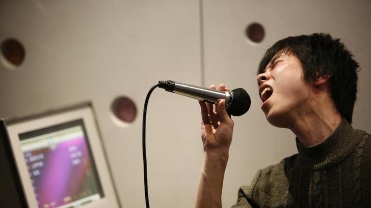 A Chinese man sings into a microphone in a Karaoke club.