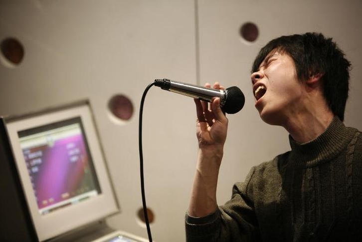 A Chinese man sings into a microphone in a Karaoke club.
