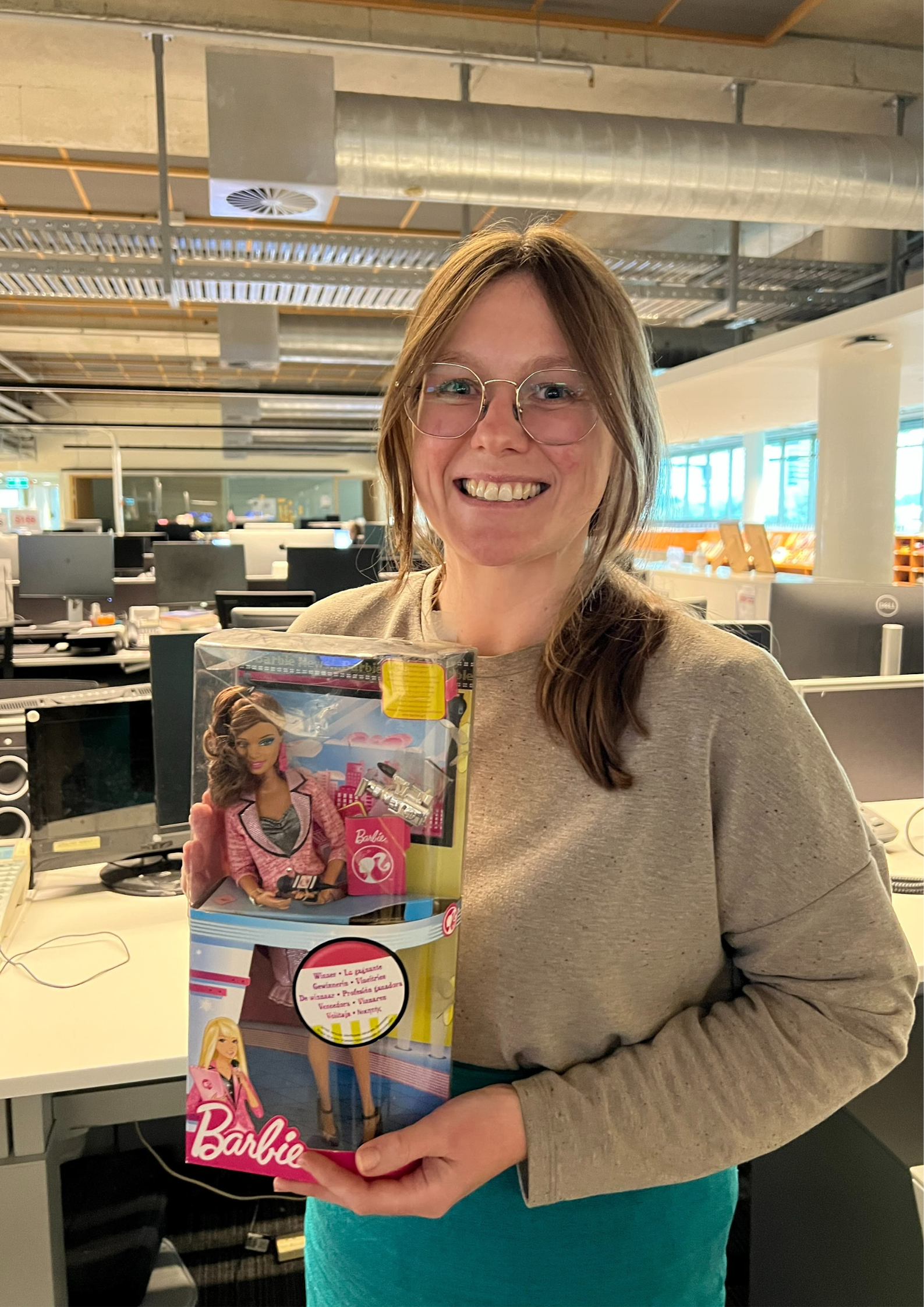 A woman holding up a Barbie doll inside its box